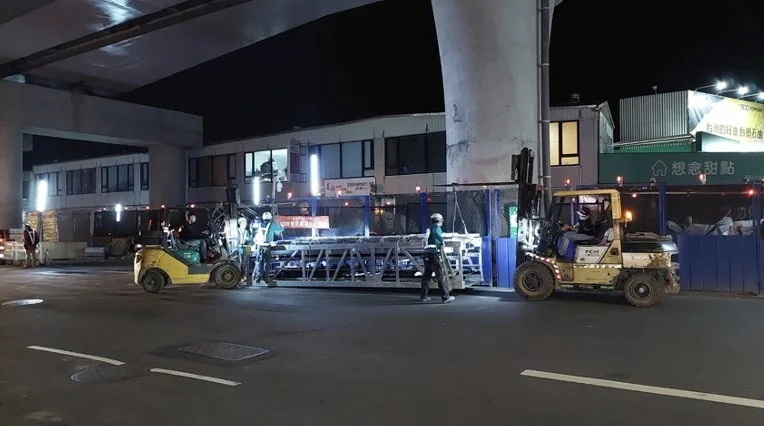 電扶梯桁架運抵現場，兩台堆高機的默契配合度超好。