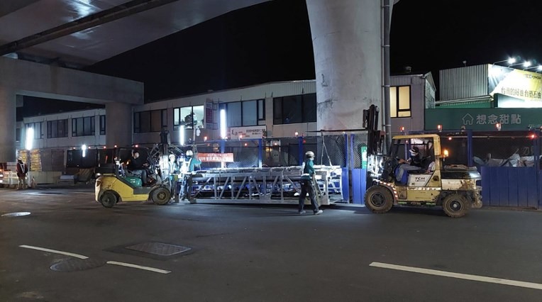電扶梯桁架運抵現場，兩台堆高機的默契配合度超好。
